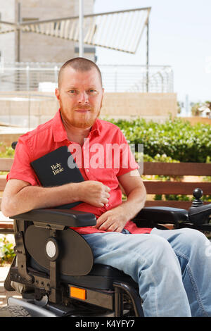 Bibel in den Händen von behinderten Menschen im Rollstuhl. Stockfoto