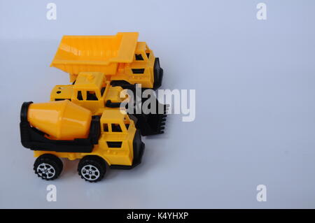 Gruppe von kleinen schwere Baumaschine Spielzeug, Lkw, Bulldozer und Betonmischer. Alle aus Kunststoff auf weißem Hintergrund. Stockfoto