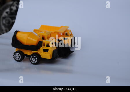 Gruppe von kleinen schwere Baumaschine Spielzeug, Lkw, Bulldozer und Betonmischer. Alle aus Kunststoff auf weißem Hintergrund. Stockfoto