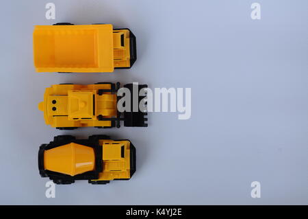 Gruppe von kleinen schwere Baumaschine Spielzeug, Lkw, Bulldozer und Betonmischer. Alle aus Kunststoff auf weißem Hintergrund. Stockfoto