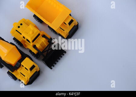 Gruppe von kleinen schwere Baumaschine Spielzeug, Lkw, Bulldozer und Betonmischer. Alle aus Kunststoff auf weißem Hintergrund. Stockfoto
