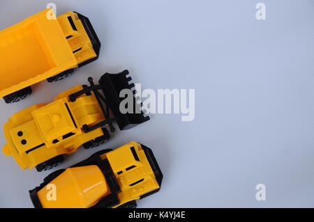 Gruppe von kleinen schwere Baumaschine Spielzeug, Lkw, Bulldozer und Betonmischer. Alle aus Kunststoff auf weißem Hintergrund. Stockfoto
