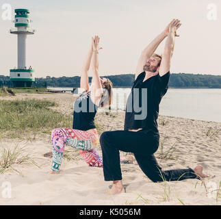 Junge passen Paar übung Yoga am Strand Dünen am frühen Morgen in Deutschland Stockfoto