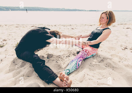 Junge passen Paar übung Yoga am Strand Dünen am frühen Morgen in Deutschland Stockfoto