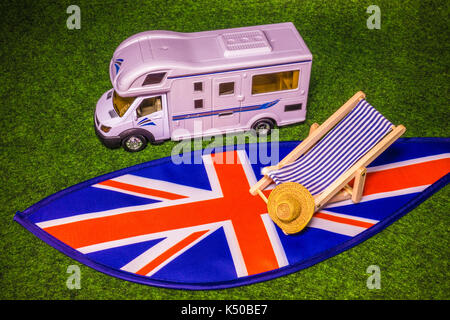 Ein Modell Wohnmobil, Auto mit Wohnwagen, Liegestuhl und Strohhut, auf Union Jack Farben. Konzept einer britischen Reisemobil oder Angaben zum Urlaub oder Tour. Stockfoto