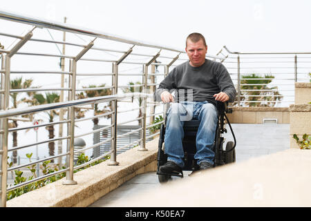 Mann im Rollstuhl sitzt in der Nähe der Geländer Stockfoto