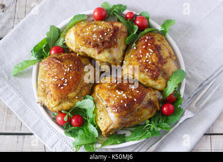 Gebackene Hühnerkeule mit Garnierung von Rucola und Tomaten. Rustikaler Stil, selektiven Fokus. Stockfoto