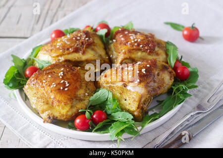 Gebackene Hühnerkeule mit Garnierung von Rucola und Tomaten. Rustikaler Stil, selektiven Fokus. Stockfoto