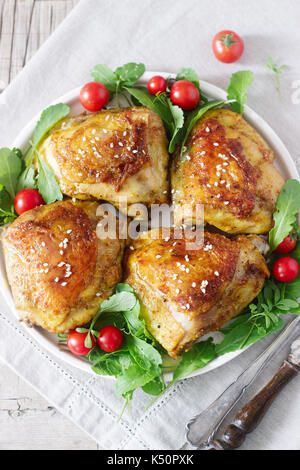 Gebackene Hühnerkeule mit Garnierung von Rucola und Tomaten. Rustikaler Stil, selektiven Fokus. Stockfoto