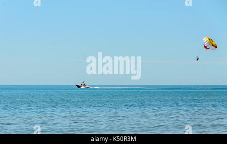 Farbige parasail Flügel mit einem Boot im Meer Wasser gezogen, auch bekannt als Parasailing oder parakiting Parasailing. Stockfoto