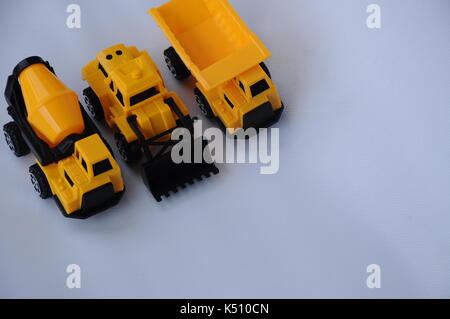 Gruppe von kleinen schwere Baumaschine Spielzeug, Lkw, Bulldozer und Betonmischer. Alle aus Kunststoff auf weißem Hintergrund. Stockfoto