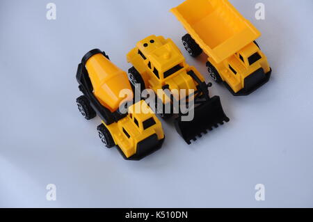 Gruppe von kleinen schwere Baumaschine Spielzeug, Lkw, Bulldozer und Betonmischer. Alle aus Kunststoff auf weißem Hintergrund. Stockfoto