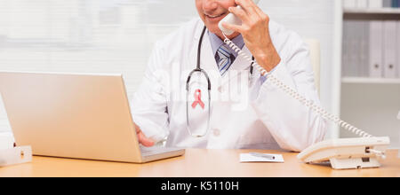 Close-up des Prostatakrebses awareness Ribbon gegen Arzt mit Laptop und am Telefon sprechen am Schreibtisch Stockfoto