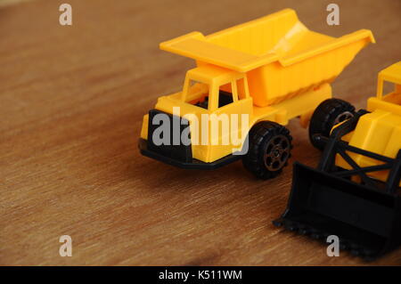Gruppe von kleinen schwere Baumaschine Spielzeug, Lkw, Bulldozer und Betonmischer. Alle aus Kunststoff auf einer Holzmaserung Textur Hintergrund isoliert. Stockfoto