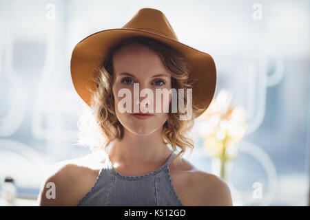 Close up Portrait von selbstbewussten jungen Frau mit Hut gegen Fenster im Coffee Shop Stockfoto