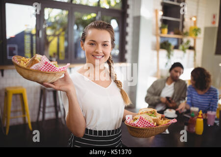 Portrait von lächelnden jungen Kellnerin mit Lebensmitteln in' im Cafe Stockfoto