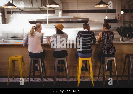 Ansicht der Rückseite des Freunde sitzen auf Hocker an der Theke im Café Stockfoto