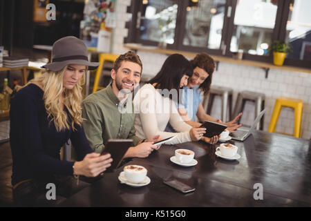 Portrait von lächelnden Mann sitzt inmitten von weiblichen Freunde am Tisch im Cafe Stockfoto