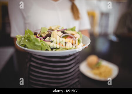 Mittelteil der Kellnerin holding Griechischer Salat frisch in der Platte im Cafe Stockfoto