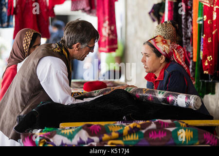 Westliche Touristen kaufen Kleidung von afghanischen Frauen auf dem Samstagsmarkt / Tadschikisch-afghanischen Freundschaftsmarkt in Khorugh, Gorno-Badakhshan in Tadschikistan Stockfoto