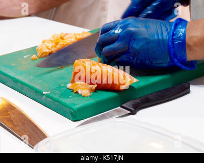 Man Schneiden von Lachs mit Pastic Handschuhe Stockfoto