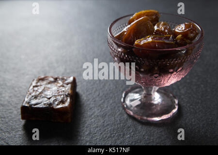 Termine Früchte in Glasschale auf Schiefer Stockfoto