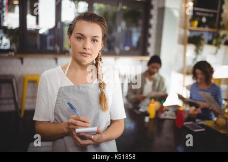 Portrait von selbstbewussten jungen Kellnerin mit Notepad im Cafe Stockfoto