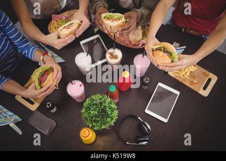 Hohe Betrachtungswinkel von Freunden Holding frisches Essen am Tisch im Café Stockfoto