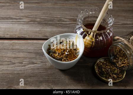 Close-up von Frühstückszerealien und Glas Honig auf hölzernen Tisch Stockfoto