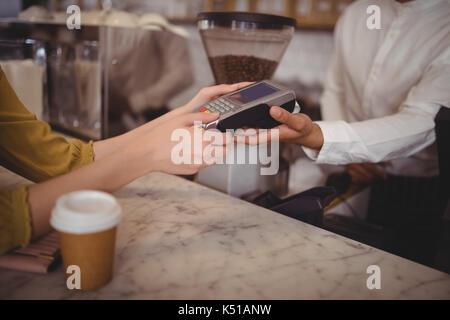 Hohe Betrachtungswinkel der weiblichen Kunden die Zahlung durch EC-Karte an der Theke im Café Stockfoto