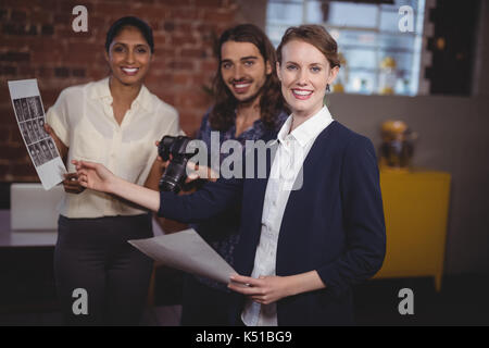 Portrait von lächelnden jungen kreativen Team diskutieren Collage im Coffee Shop Stockfoto