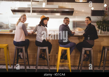 Rückansicht Portrait von lächelnden jungen Freunde sitzen auf Hockern an der Theke im Café Stockfoto