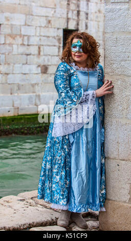 Venedig, Italy-March 2, 2014: Bild einer Frau verkleidet in einem blauen Kostüm versteckt neara eine Mauer endge eines Wasser Kanal in Venedig während der carniv Stockfoto