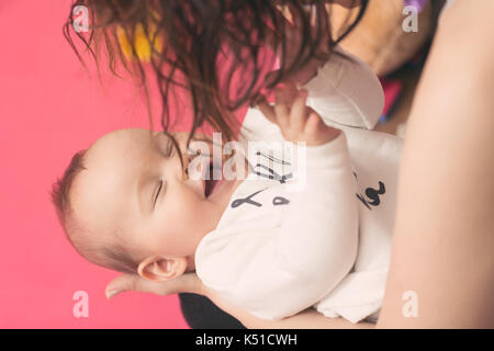 Mutter Holding Baby in den Armen und mit ihr spielen, Mädchen lächelnd und Ihr Haar berühren; instagram Stil Effekt angewendet werden Stockfoto