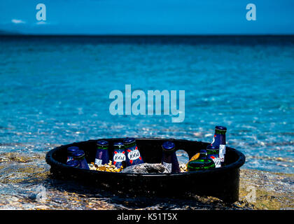 Leere Bierflaschen in einem schwarzen Eimer am Strand Stockfoto