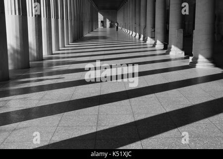 Athen, Griechenland - 14. Oktober 2015: Der Mann, der zu Fuß auf die Spalten von Stoa attalos an den antiken Agora. Licht und Schatten abstrakt Architektur schwarz ein Stockfoto
