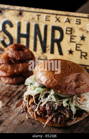 Südliche Texas style BBQ zog Pork Sandwich mit bleu Käse slaw und Dill Pickles auf rustikalen Hintergrund Stockfoto