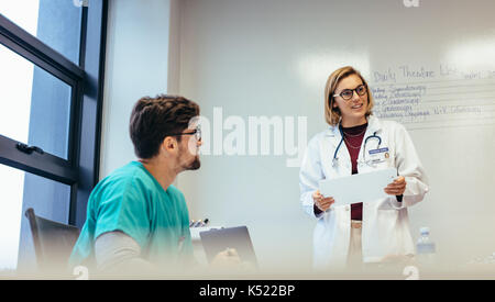 Ärztin führende Konferenz im Krankenhaus. Medizin professionelles Briefing ihr Team im Sitzungssaal. Stockfoto