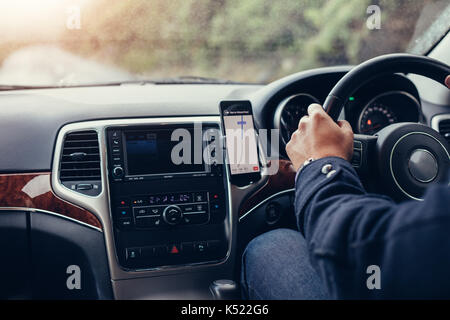 Mann fahren Auto mit mobilen Navigationssystem. Mann mit Handy mit Karte gps-Navigation im Auto. Stockfoto