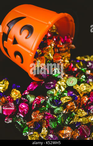 Hohe Betrachtungswinkel von orange Schaufel mit Schokoladen auf schwarzem Hintergrund Stockfoto