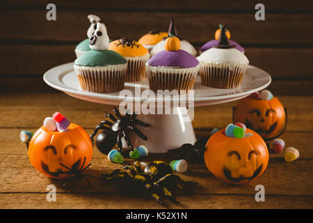 Cup Cakes mit Dekorationen auf hölzernen Tisch während der Halloween Stockfoto