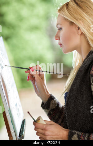 Frau artist mit einem Pinsel in der Hand zieht auf Leinwand Stockfoto