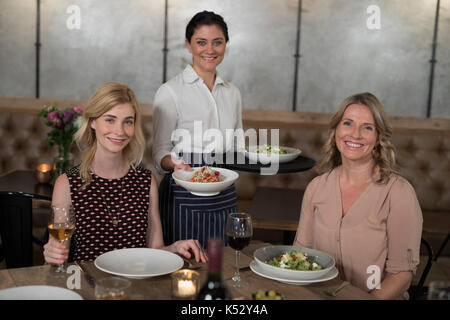 Portrait von Happy Kellnerin und Kunden an den Esstisch im Restaurant Stockfoto