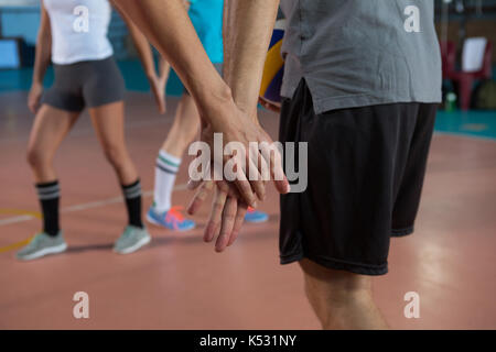 Zugeschnittenes Bild von Volleyball Spieler die Hand mit Mannschaftskameraden am Hof Stockfoto