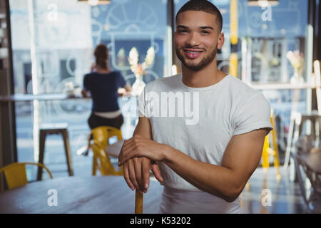 Portrait von lächelnden Kellner mit weiblichen Kunden im Hintergrund im Cafe Stockfoto