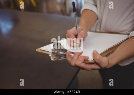 Den mittleren Abschnitt der Kellnerin auf Papier beim Stehen in der Cafe Stockfoto