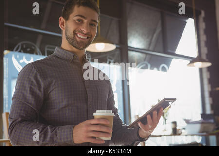 Porträt der glückliche junge Mann mit digitalen Tablet während Kaffee im Cafe Stockfoto