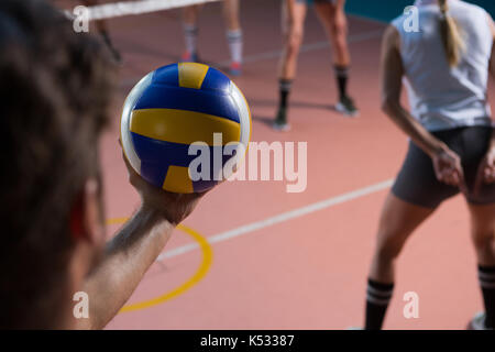 7/8 Hand der Spieler mit Volleyball durch weibliche Mannschaftskameraden am Hof Stockfoto