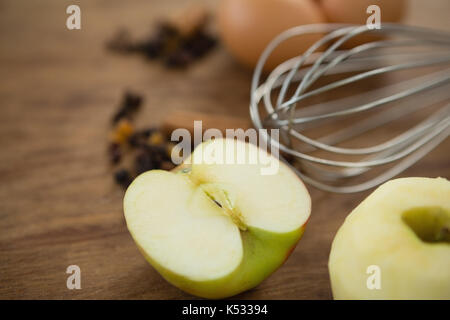 Nahaufnahme von Kabel Schneebesen durch Eier Granny Smith Apfel auf dem Tisch Stockfoto