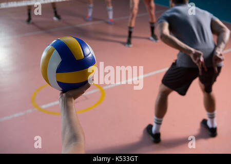 7/8 Hand der Spieler mit Volleyball durch Mannschaftskameraden am Hof Stockfoto